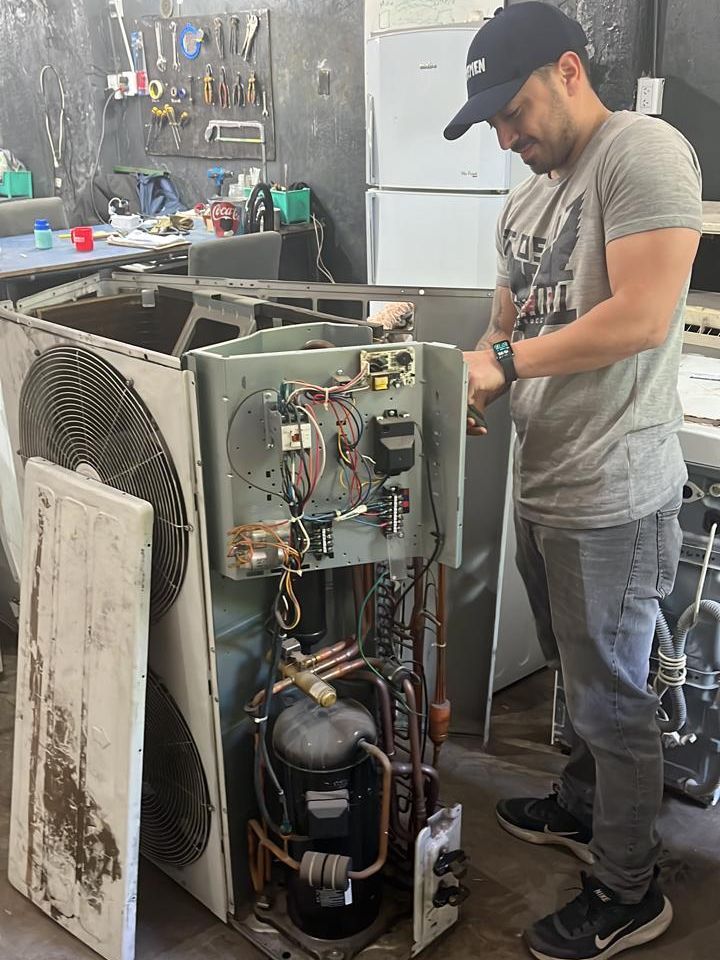 Técnico revisando la parte eléctrica y el compresor de una unidad exterior en el taller de BAYAC